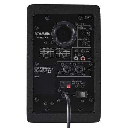 Rear panel of the black Yamaha HS4 left speaker, showing the Room Control and High Trim switches, stereo mini and RCA LINE 2 inputs, combo XLR/TRS LINE 1 inputs and the output terminals to the right speaker