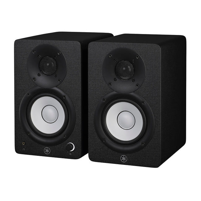 Yamaha HS4 powered studio monitors in black, angled pair view showing the left speaker's front volume knob and headphone jack