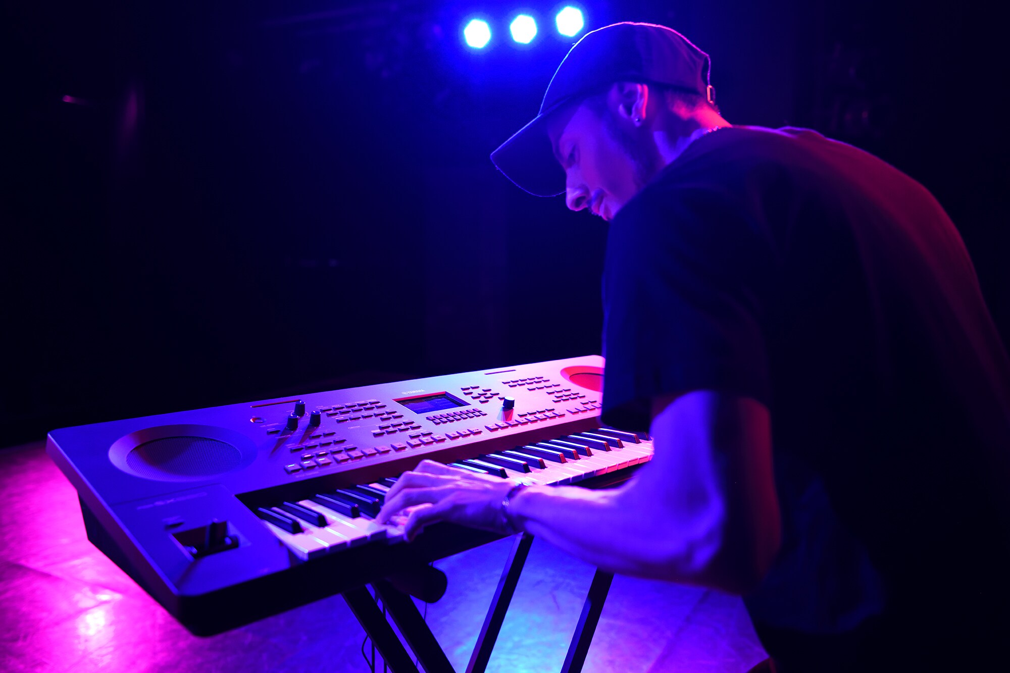 Musician performing on the Yamaha PSR-SX620 under violet stage lighting
